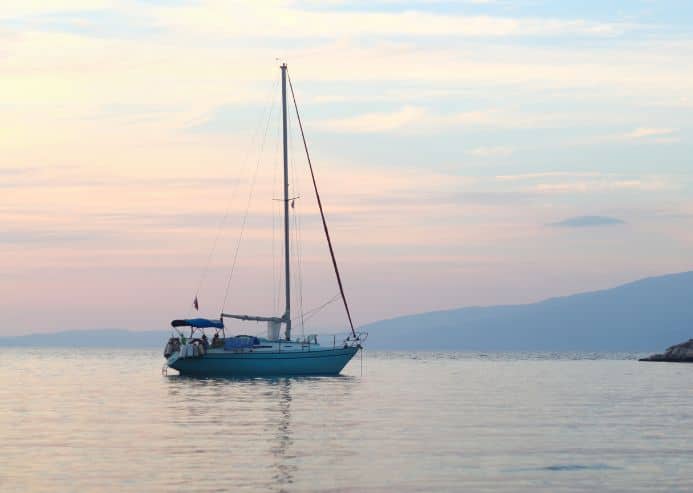 Photo bateau dans une crique corse au coucher du soleil pour la location de voilier en Corse avec skipper par My Way Yachting.