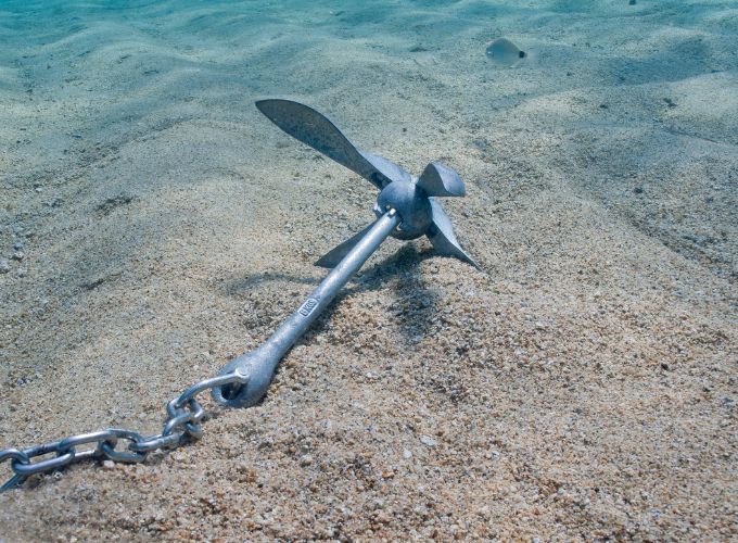 photo d'une ancre au fond de l'eau posée sur le sable - attention au mouillage en mer pour ne pas abimer les fonds marins corses.